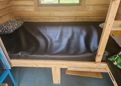 Lit du bas avec oreiller dans la cabane Le Poulailler près du poêle à bois