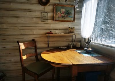 Coin repas rustique à Jack's Camp avec table en bois et vue sur la forêt enneigée